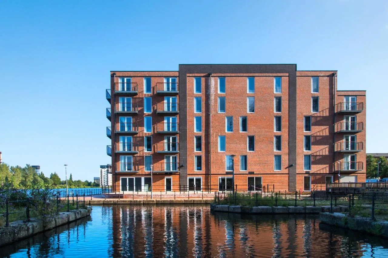 a large red brick building next to a body of water at Staybridge Suites - Cardiff by IHG in Cardiff