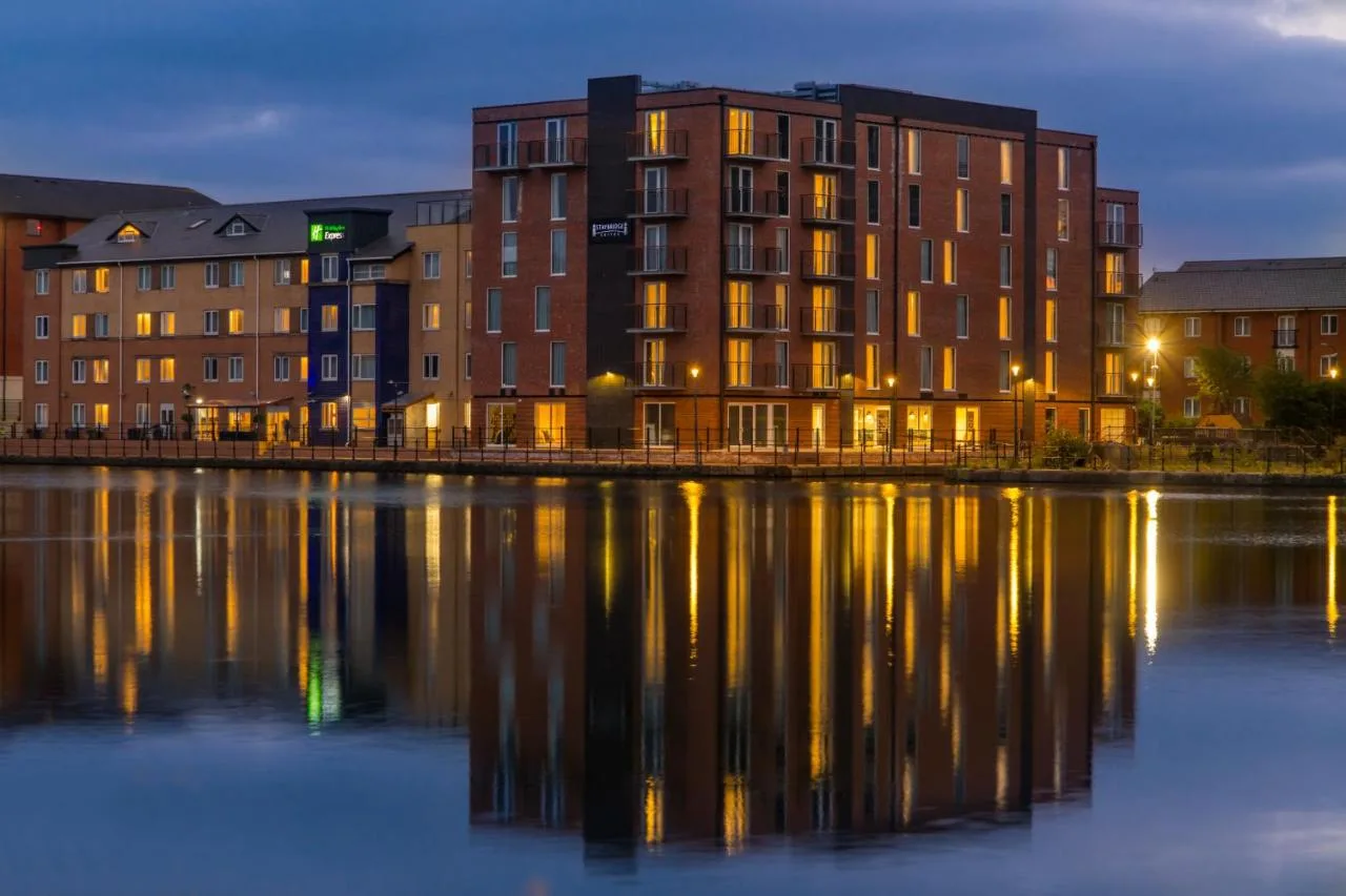 a building next to a body of water at night at Staybridge Suites - Cardiff by IHG in Cardiff