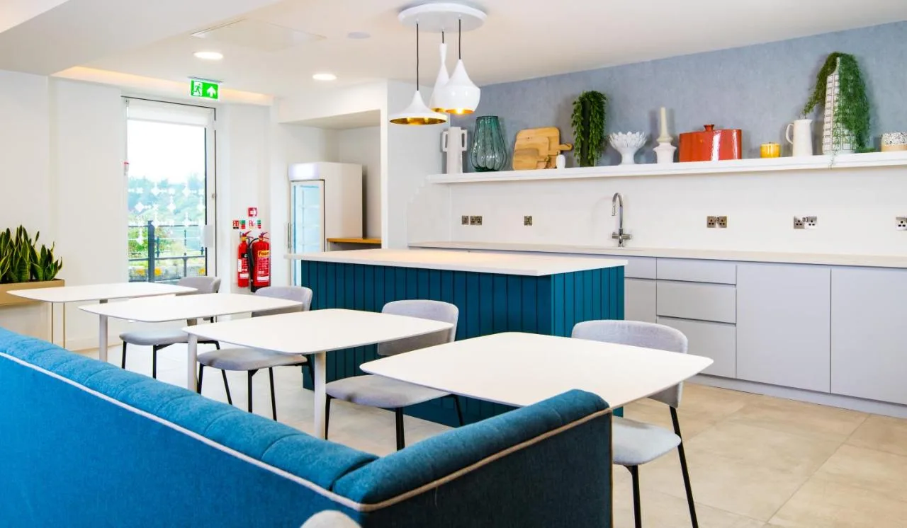 a restaurant with tables and a blue couch at Staybridge Suites - Cardiff by IHG in Cardiff